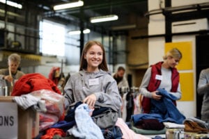 Volunteers sorting out donated clothes in community charity donation center, coronavirus concept.