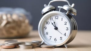 Next to a clock is a pile of coins, symbolizing the phrase "time is money."